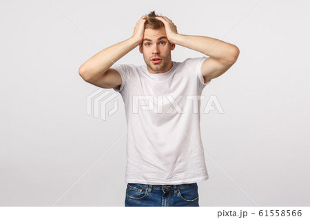 Alarmed and frustrated, blond guy in panic, grab head and stare camera speechless, feeling nervous, dont know what do, standing indecisive, have problems, posing troubled white background 61558566