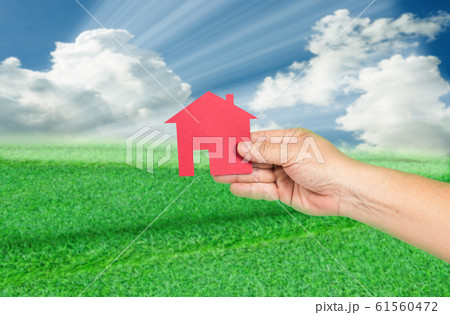 Red house in hand with landscapes background. Real 61560472