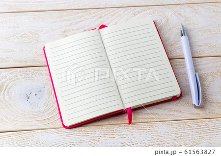 Opened lined paper notebook in a pink cover and white ballpoint pen on a white wood textured surface Opened lined paper notebook in a pink cover and white ballpoint pen on a white wood textured surface 61563827