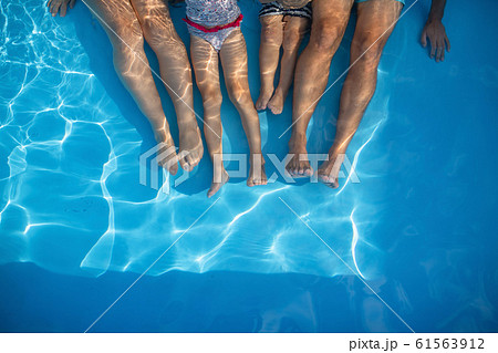 Midsection of family with small children sitting in swimming pool outdoors. 61563912