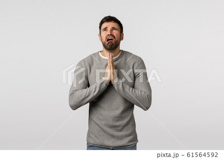 Miserable and distressed young pathetic bearded guy asking mercy, praying god hear prayers, hold hands together over chest, crying and complaining unfair life, want wish come true, white background 61564592