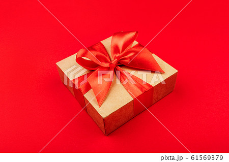 Cardboard gift box with bow on red background. 61569379