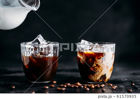Pouring milk into a glass of espresso coffee with Pouring milk into a glass of espresso coffee with 61570935