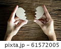 woman hand holding broken heart paper cut on wooden background 61572005
