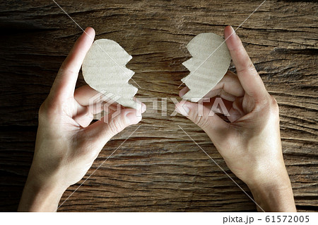 woman hand holding broken heart paper cut on wooden background woman hand holding broken heart paper cut on wooden background 61572005