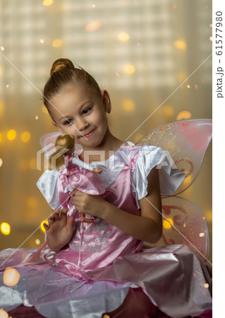 little fairy in a pink dress playing with a doll 61577980