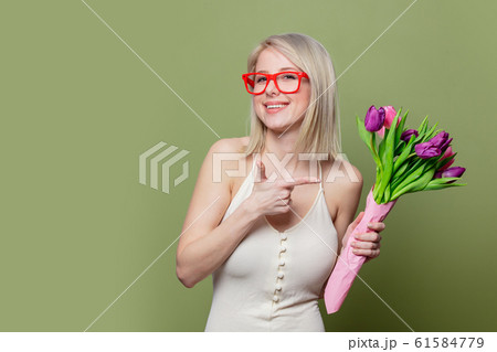 Surprised blonde girl with tulips on green background Surprised blonde girl with tulips on green background 61584779