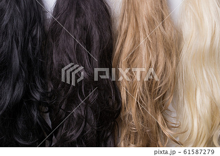 Women's wigs of different shades. Blonde brunette brown-haired woman. Women's wigs of different shades. Blonde brunette brown-haired woman. 61587279