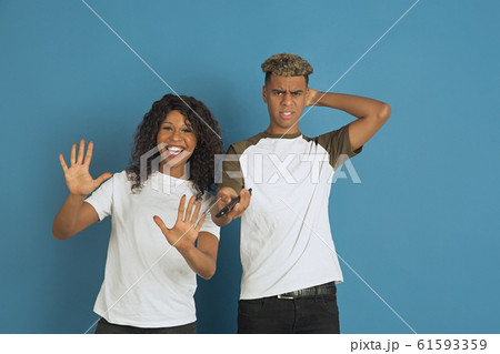 Young emotional african-american man and woman on blue background 61593359
