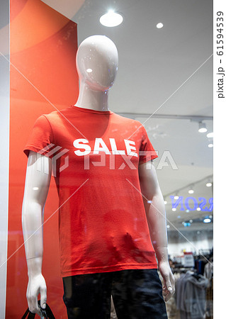 some mannequins wear a red shirt with the word "sale" in the window of an Italian clothing and fashion store. During the winter sales in January. 61594539