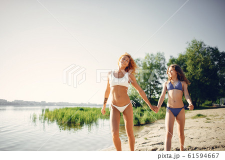 Sporty mother with cute daughter walking near lake Sporty mother with cute daughter walking near lake 61594667