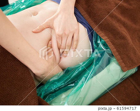 明るい店内でお腹の揉み出しを受ける女性	 61594717
