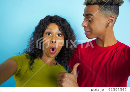 Young emotional african-american man and woman on blue background Young emotional african-american man and woman on blue background 61595542