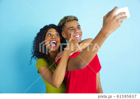 Young emotional african-american man and woman on blue background Young emotional african-american man and woman on blue background 61595637