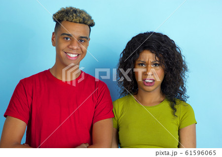 Young emotional african-american man and woman on blue background 61596065