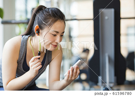 トレーニング休憩時、スマホで音楽を聴く女性 61596780