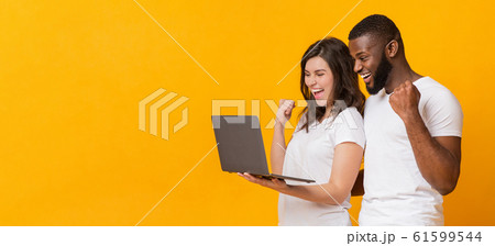 Joyful multiracial couple rejoicing success with laptop, exclaiming with excitement Joyful multiracial couple rejoicing success with laptop, exclaiming with excitement 61599544