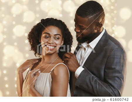 Man in suit putting golden chain on happy lady neck Man in suit putting golden chain on happy lady neck 61600742