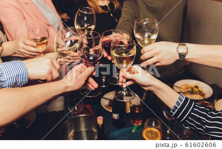 Close up shot of group of people clinking glasses with wine or champagne in front of bokeh background. older people hands. 61602606