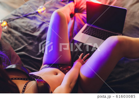Beautiful, young girl posing in front of a web camera, working as a model. The concept of online flirting. 61603085