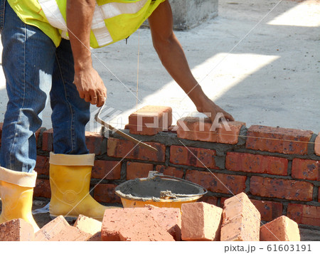 Bricklayer lay bricks block to form building walls at the construction site.  61603191