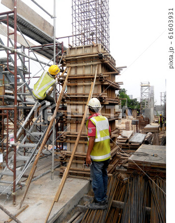 Construction workers fabricating column timber form work and reinforcement bar at the construction site in Malacca, Malaysia.  61603931