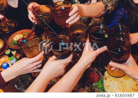 Close up shot of group of people clinking glasses with wine or champagne in front of bokeh background. older people hands. 61603987