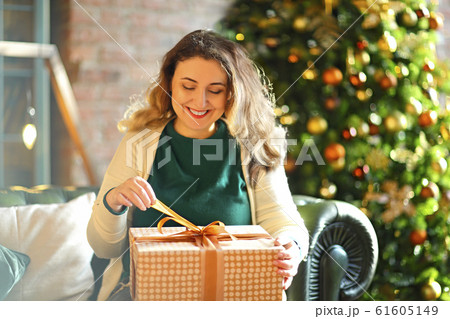 Smiling happy woman with gift box over living room Smiling happy woman with gift box over living room 61605149