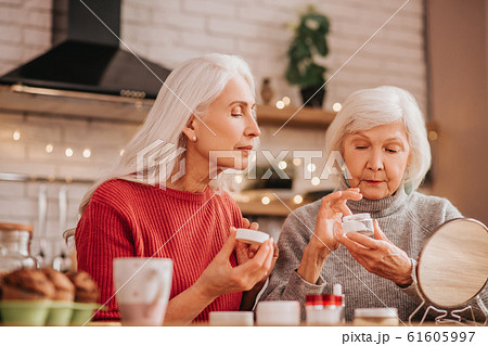 Two good-looking elderly women applying new cream Two good-looking elderly women applying new cream 61605997