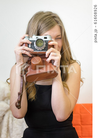Young woman holds a retro camera in her hands, 61608926