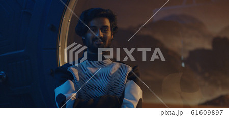 Male astronaut looking out of Mars base window 61609897