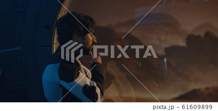 Male astronaut looking out of Mars base window Male astronaut looking out of Mars base window 61609899