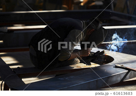 welder working with electrode at semi-automatic arc welding in manufacture production plant.Selective focus welder working with electrode at semi-automatic arc welding in manufacture production plant.Selective focus 61613683