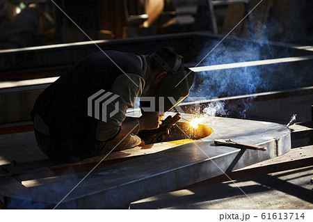 welder working with electrode at semi-automatic arc welding in manufacture production plant.Selective focus 61613714
