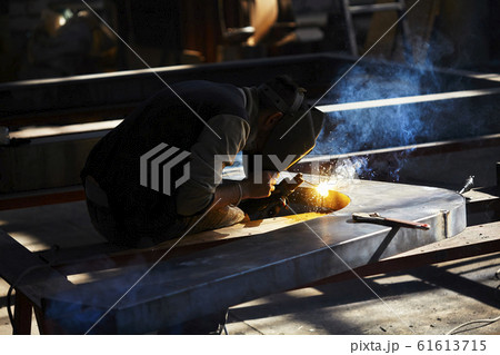 welder working with electrode at semi-automatic arc welding in manufacture production plant.Selective focus welder working with electrode at semi-automatic arc welding in manufacture production plant.Selective focus 61613715