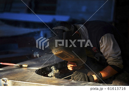welder working with electrode at semi-automatic arc welding in manufacture production plant.Selective focus welder working with electrode at semi-automatic arc welding in manufacture production plant.Selective focus 61613716
