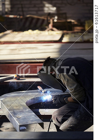 welder working with electrode at semi-automatic arc welding in manufacture production plant.Selective focus welder working with electrode at semi-automatic arc welding in manufacture production plant.Selective focus 61613717
