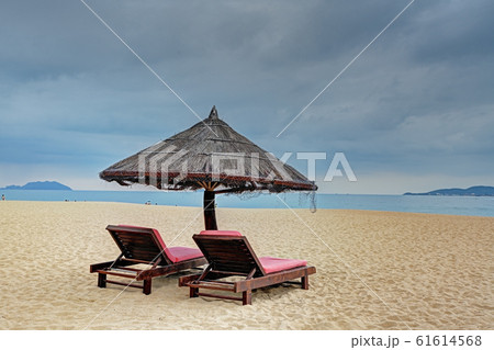 Two loungers under straw parasol at the beach  61614568
