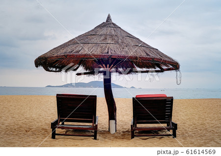 Two loungers under straw parasol at the beach  61614569