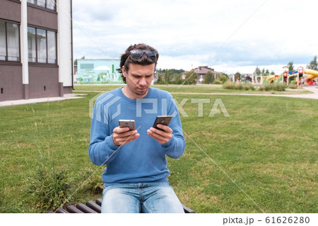 Man is typing a messages on two mobile phones. 61626280