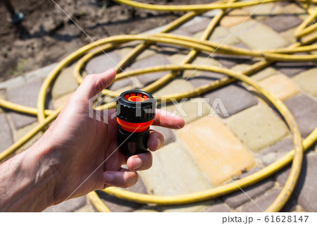 Connector in the male hand for a watering hose at the dacha. Close-up. 61628147
