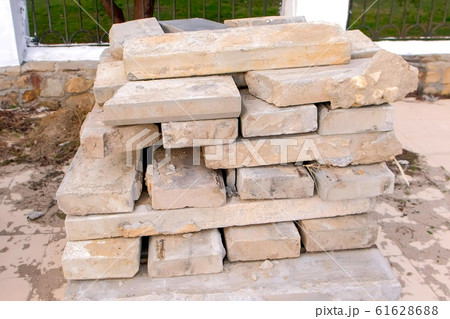 Laying dismantled old paving slabs in pile on sidewalk in city park. 61628688