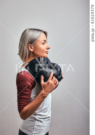 Young beautiful sexy woman boxer posing with black boxing gloves in her hands on a gray background. Copy space, gray background, goal achievement. 61629379