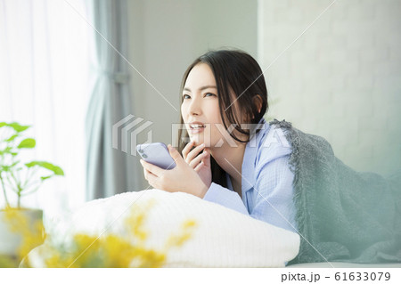 女性　寝坊　パジャマ　ベッド　寝起き　スマホ　スマートフォン 61633079