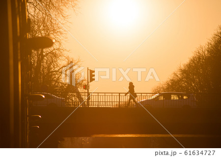 Silhouette of woman walking on bridge under the river by sunset Silhouette of woman walking on bridge under the river by sunset 61634727