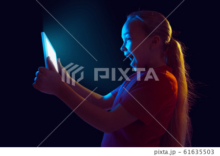 Caucasian girl's portrait isolated on dark studio background in neon light Caucasian girl's portrait isolated on dark studio background in neon light 61635503