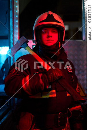 Close up firefighter male with hammer on his shoulder standing near fire engine Close up firefighter male with hammer on his shoulder standing near fire engine 61637512