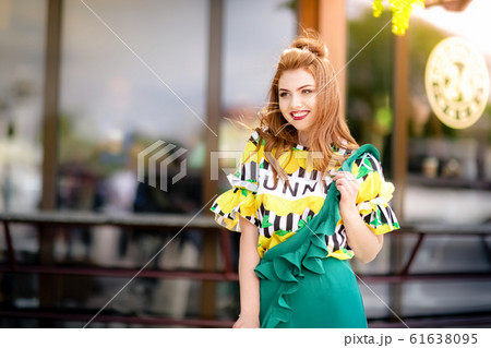 A woman walks down the street along tourist cafes in bright attractive clothes A woman walks down the street along tourist cafes in bright attractive clothes 61638095