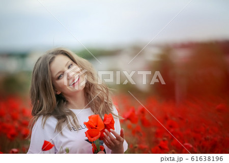 Beautiful happy smiling teen girl portrait with red flowers on head enjoying in poppies field nature background. Makeup and curly hair style. Lifestyle. 61638196