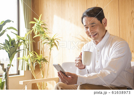 リビングでスマホでネットを見るミドル〜シニア男性 61638973